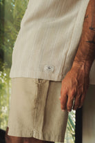 Homem usando BERMUDA SARJA HAMIE - CAQUI da Greenish, estilo minimalista urbano com 43 cm de comprimento e bolso verdugo.