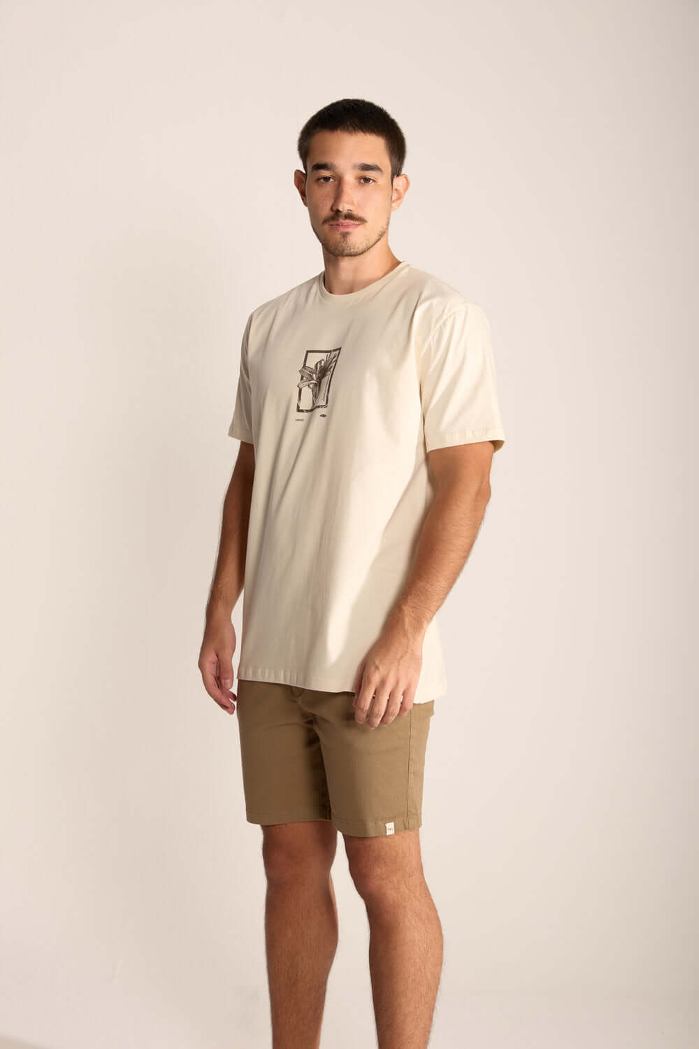 Modelo masculino usando camiseta clara e bermuda caqui, destacando estilo e conforto casual.