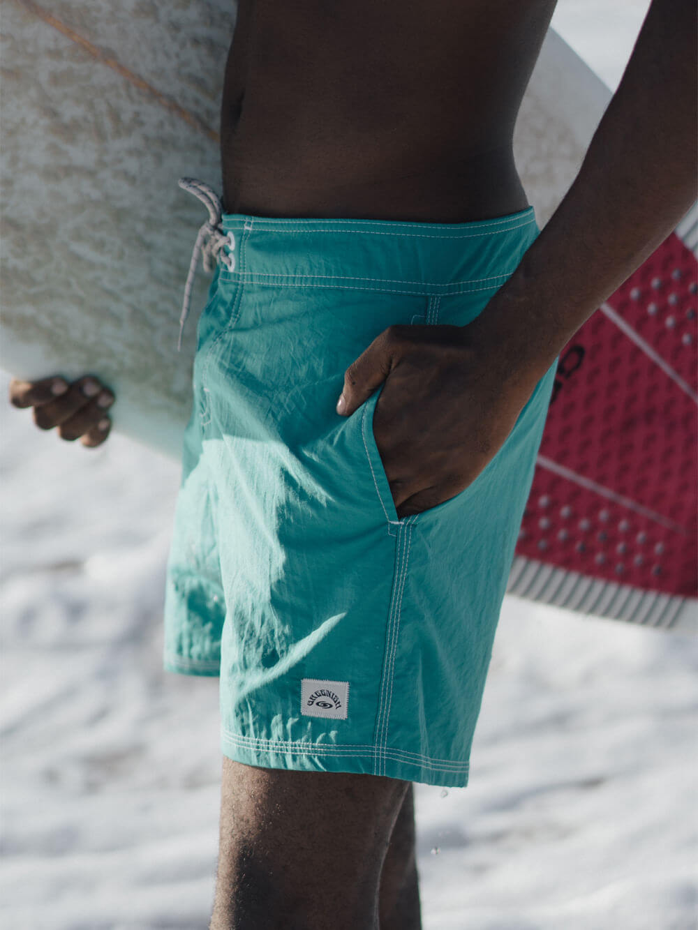 Sunga turquoise à beira da praia, surfista segurando prancha, estilo descontraído, moda de verão.