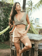 Modelo usando Blusa Sara verde da marca Greenish, com caimento cropped e decote em V, combinada com shorts claros.