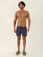 Modelo vestindo o Boardwalk Sunshine Azul Marinho da Greenish, shorts de praia confortáveis com detalhe na cintura.