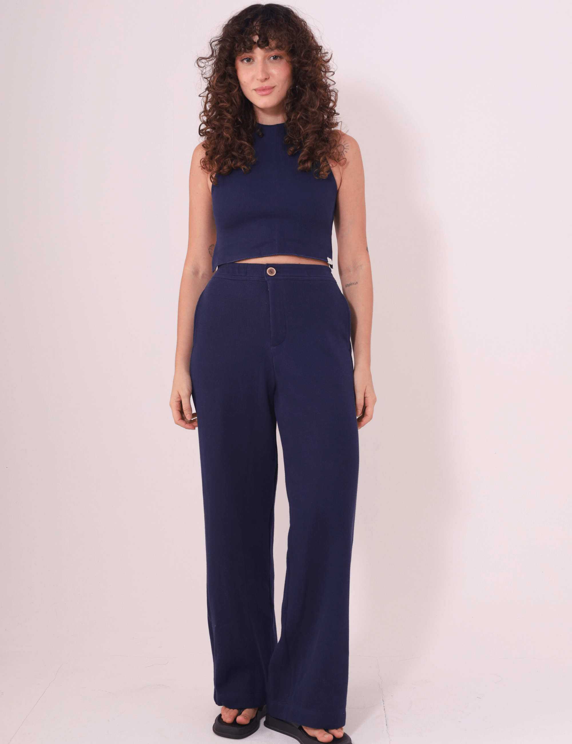 Mulher vestindo Calça Lina azul marinho da Greenish, feita em Tricot Bloom 100% algodão, com caimento reto e cintura média.