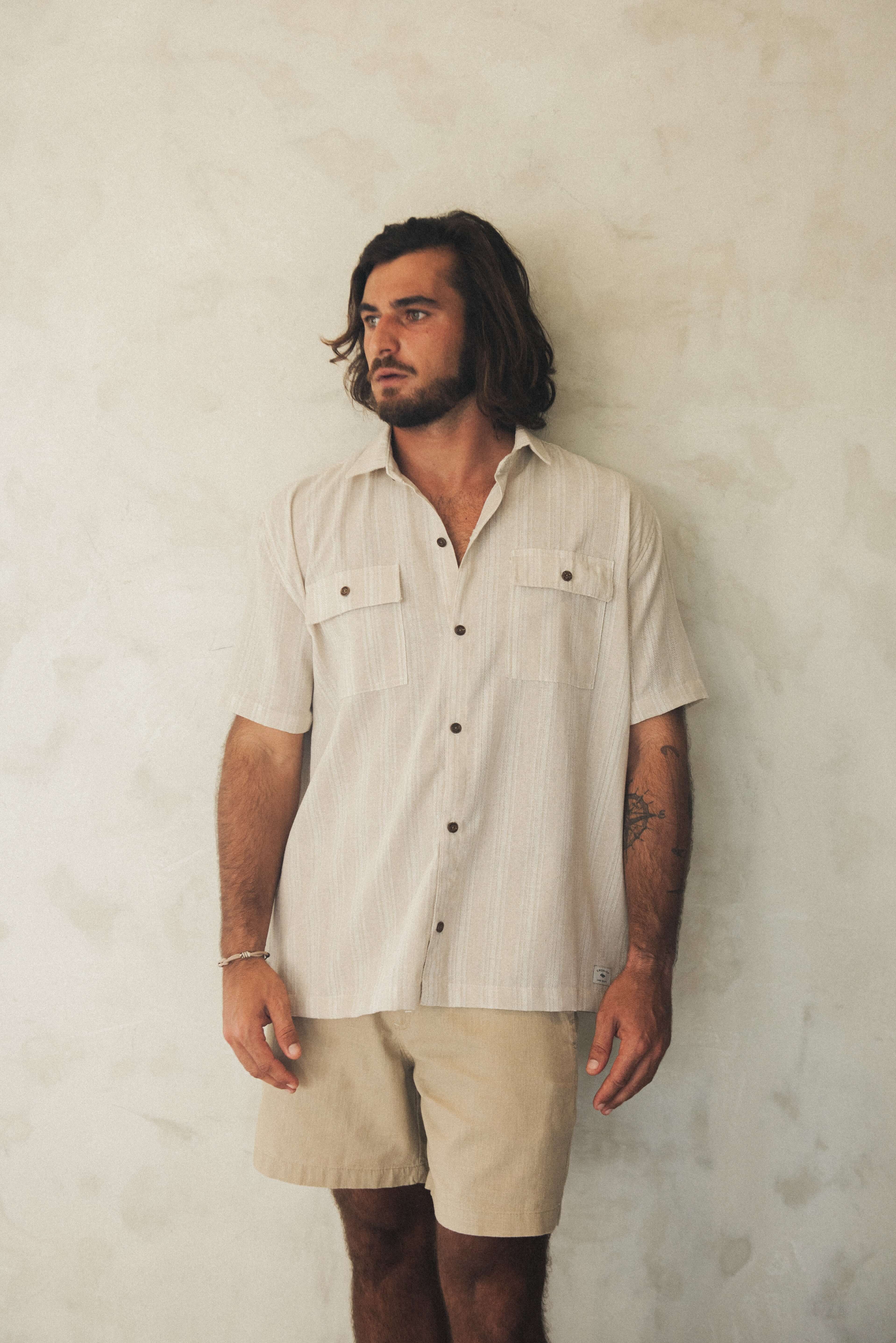 Homem vestindo Camisa Botão Linho Listrado Oversized - Natural da Greenish, com design utilitário e botões de coco, ideal para looks casuais.