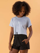 Camiseta cropped em azul claro com estampa, usada por modelo com cabelo cacheado, da marca Greenish.