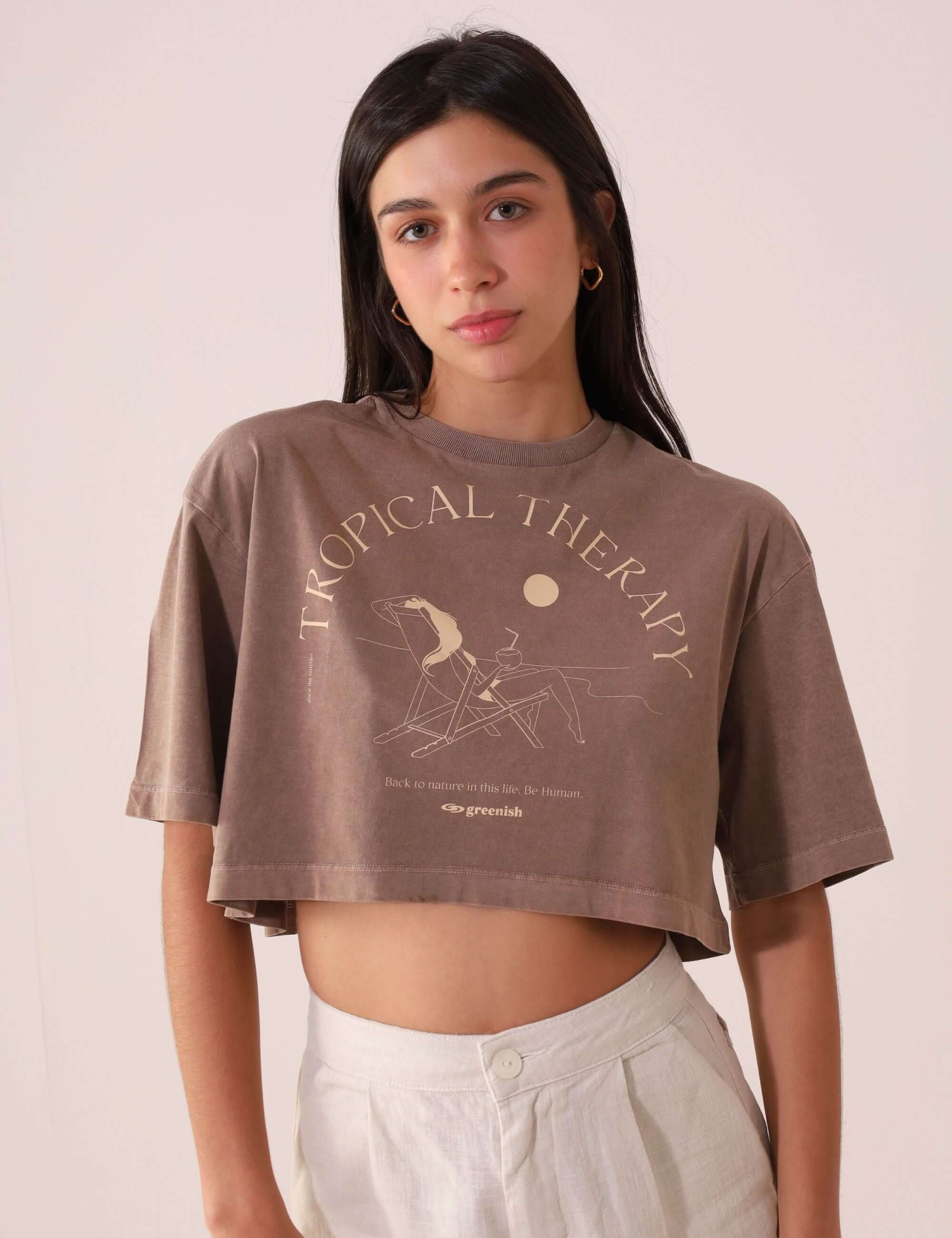 Mulher vestindo camiseta Greenish CROPPED STONE RELAXING VIEW - MARRON, estilo oversized, com estampa Tropical Therapy vintage.