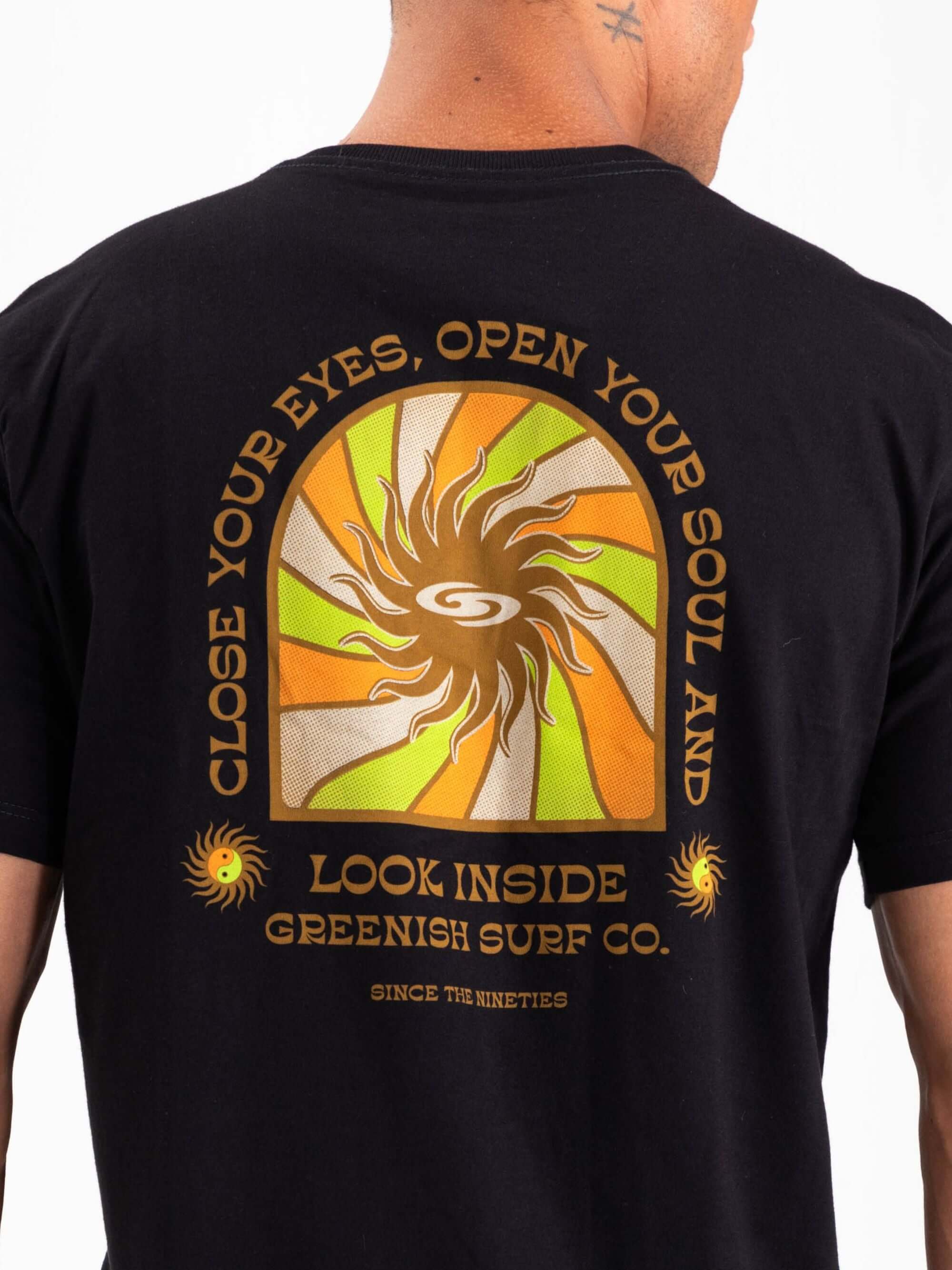 Camiseta preta Greenish com estampa de sol e slogan "Close Your Eyes, Open Your Soul" ao fundo.