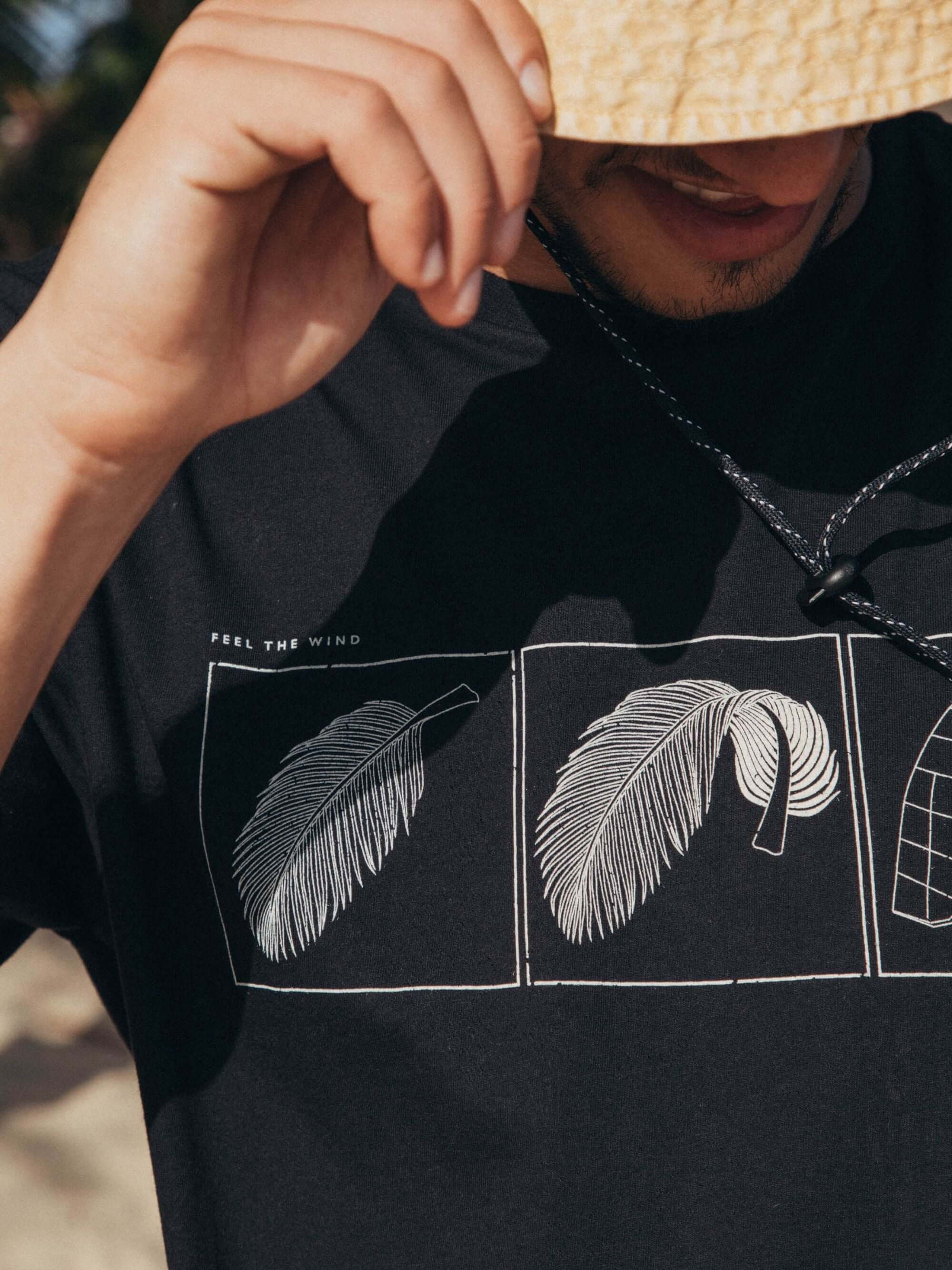 Camiseta preta Feel The Wind da Greenish, com estampa minimalista de penas, ideal para dias ensolarados.