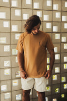 Modelo veste Camiseta Greenish Quality Product - Caqui em cenário casual, destacando design minimalista e conforto diário.