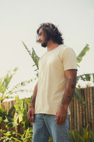 Homem usando CAMISETA STONE RAWEDGE - AREIA da Greenish em cenário tropical, camiseta de algodão com visual raw e despojado.