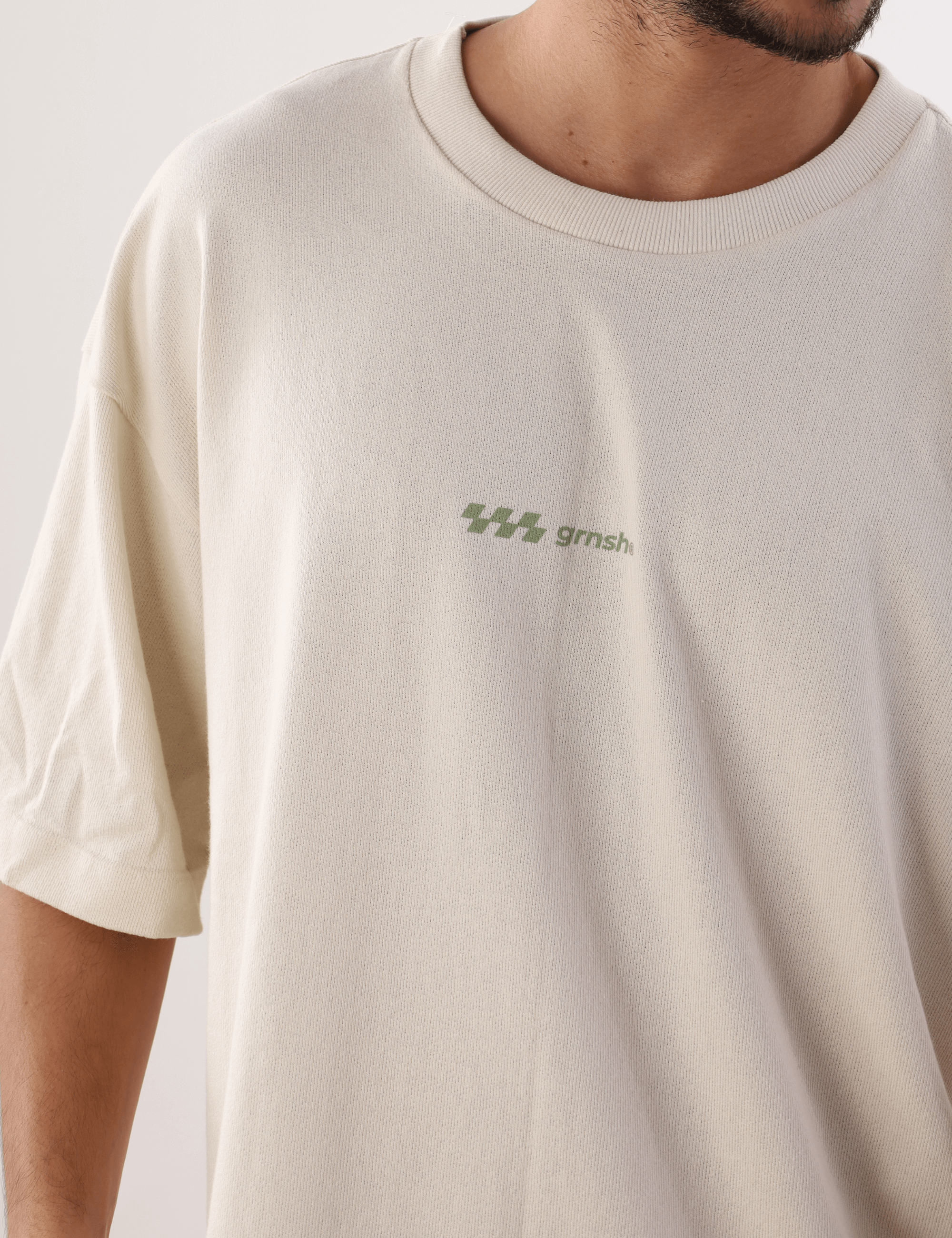 Camiseta Oversized Hexagon Lines Bege da marca Greenish, confortável e moderna, destacando logo minimalista em detalhe frontal.