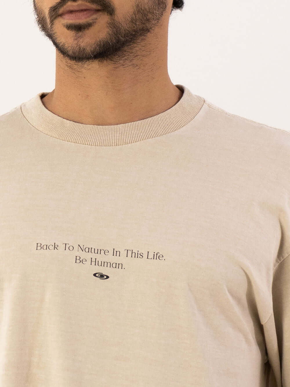 Camiseta oversized da Greenish em tom bege, com estampa minimalista "Back To Nature In This Life, Be Human".