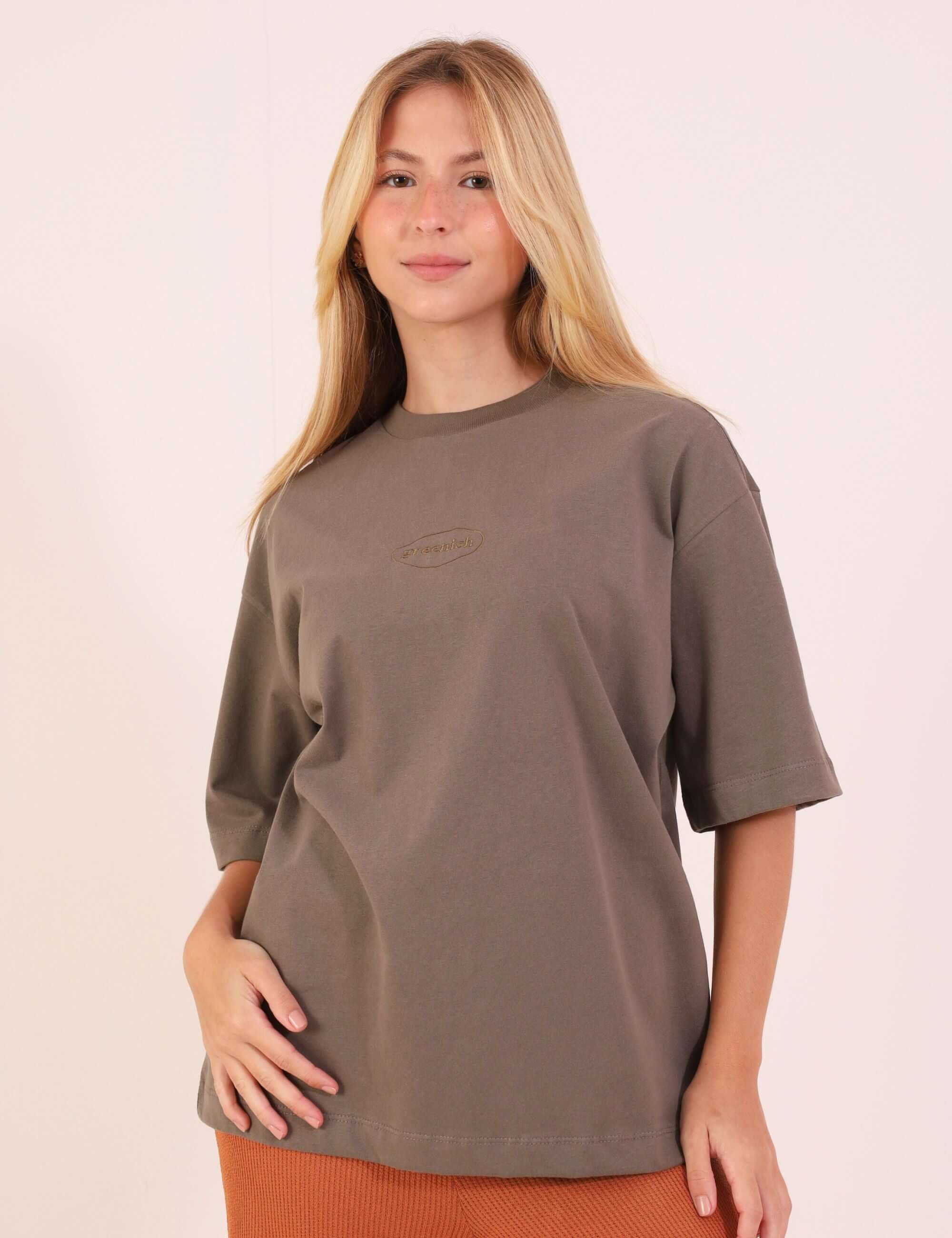 Modelo vestindo CAMISETA OVERSIZED GREENISH BORDADA - VERDE ESCURO, destacando o caimento soltinho e a suavidade do tecido de algodão.
