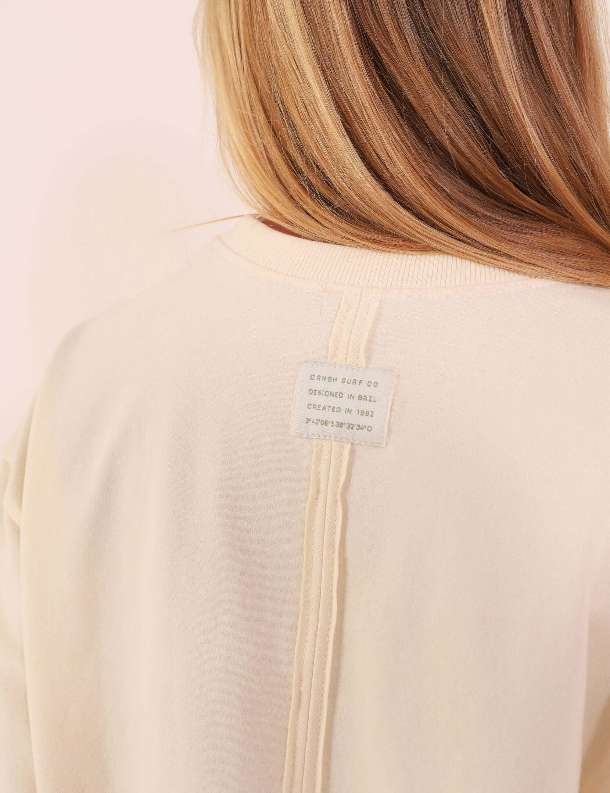 Etiqueta e recorte posterior da Camiseta Oversized Breeze - Bege, detalhando o design moderno e confortável.