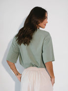 Mulher usando camiseta oversized Enjoy The Now verde da Greenish, estilo despojado e confortável.