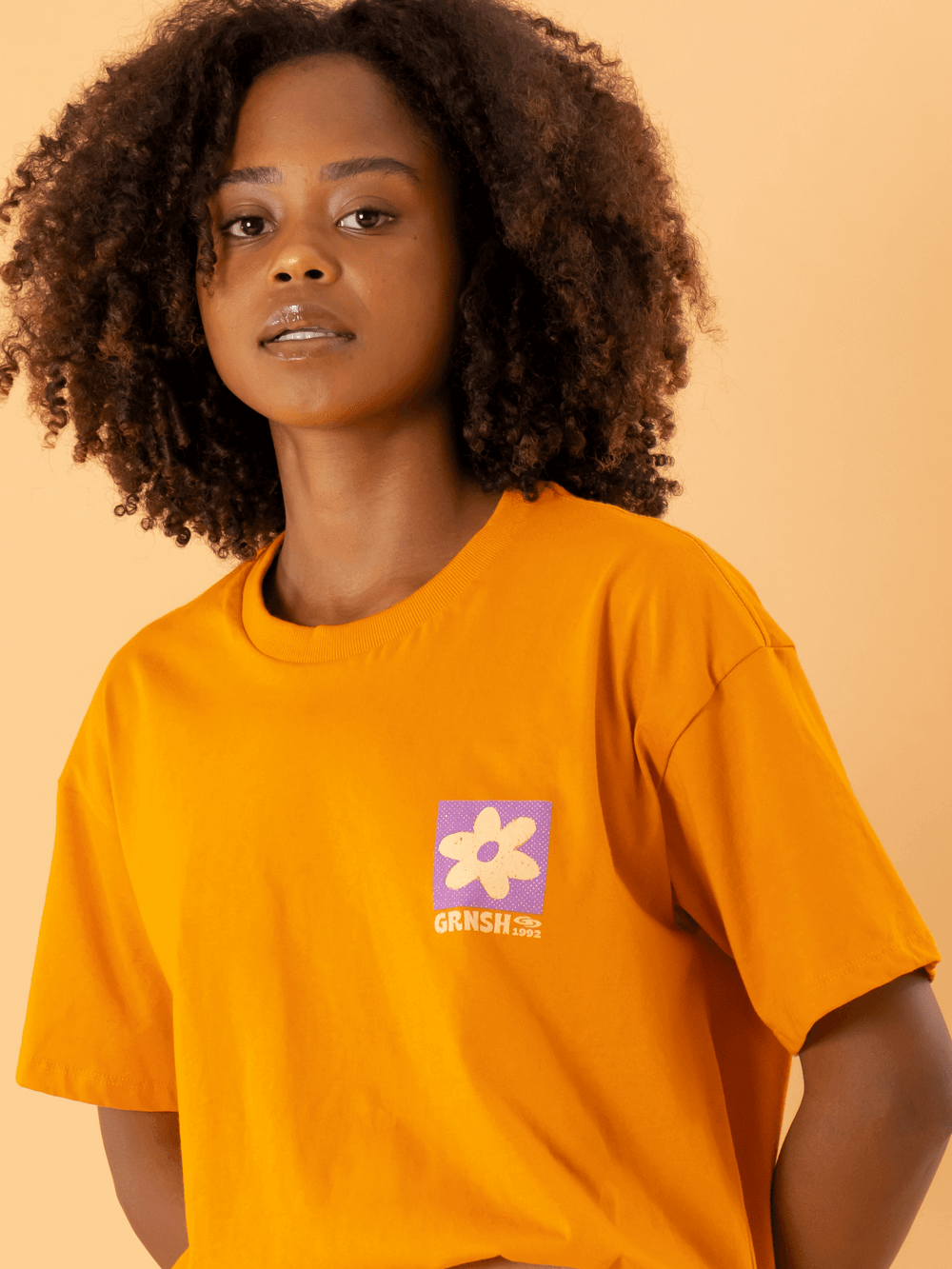 Camiseta oversized laranja da marca Greenish com estampa de flor, estilo moderno e versátil.