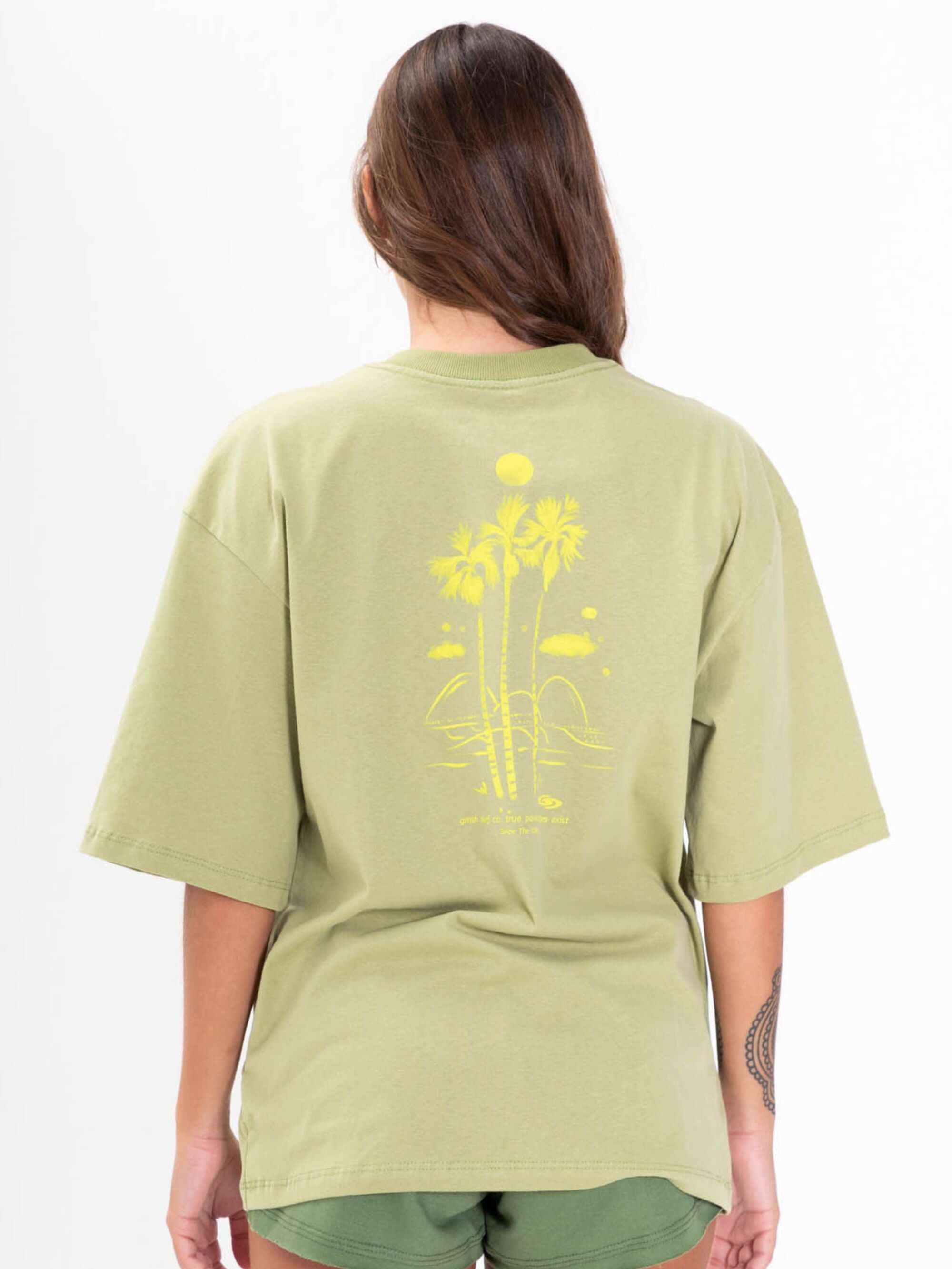 Camiseta oversized verde da Greenish com estampa colorida de palmeiras nas costas.