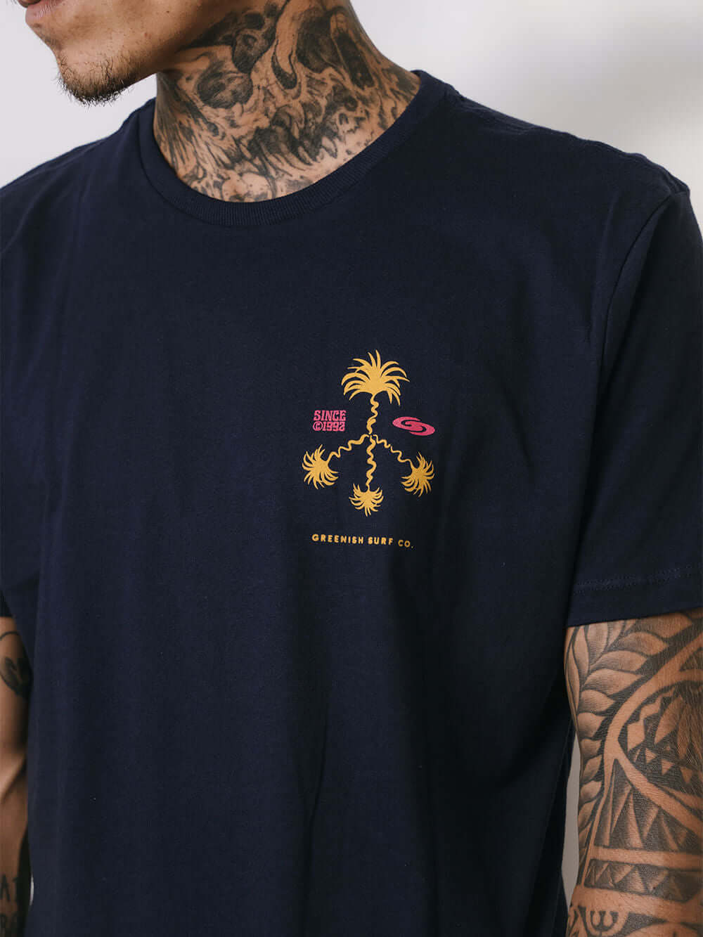 Camiseta azul marinho da Greenish com estampa divertida de palmeiras e detalhes em amarelo e rosa.