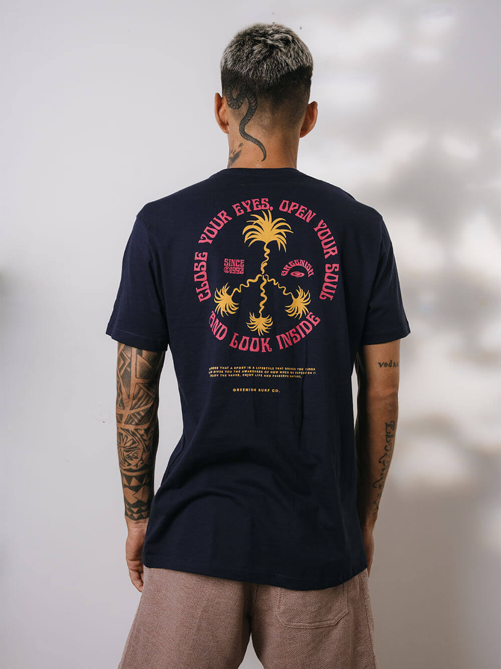 Modelo usando camiseta azul marinho da Greenish com estampa tropical nas costas, ideal para qualquer ocasião.