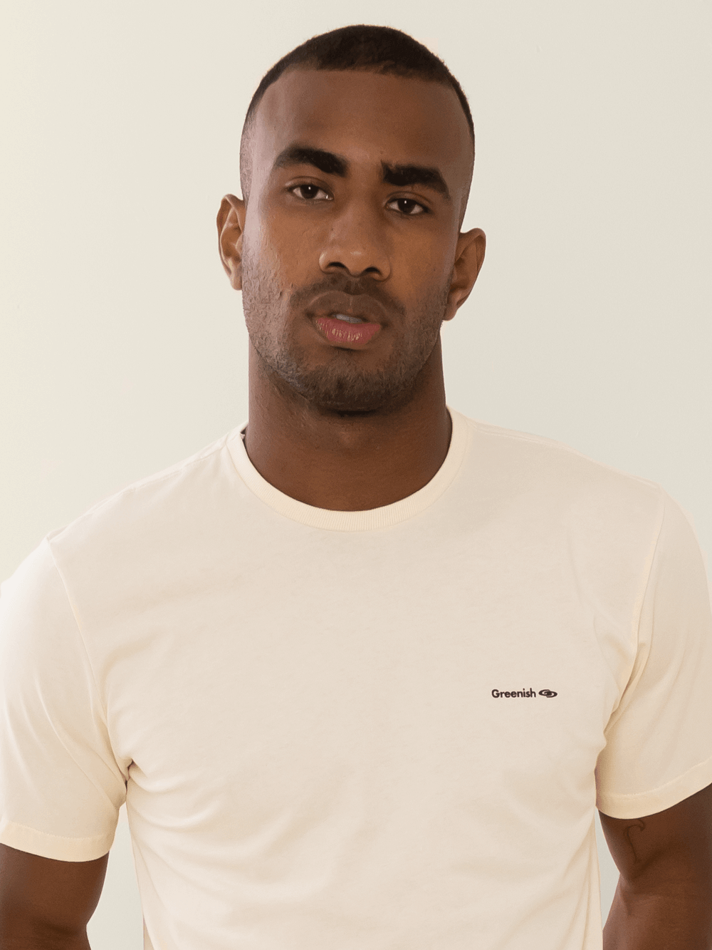 Camiseta bege minimalista com logo Greenish em malha 100% algodão sustentável.
