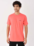 Camiseta coral com logo minimalista da Greenish, feita em algodão sustentável.