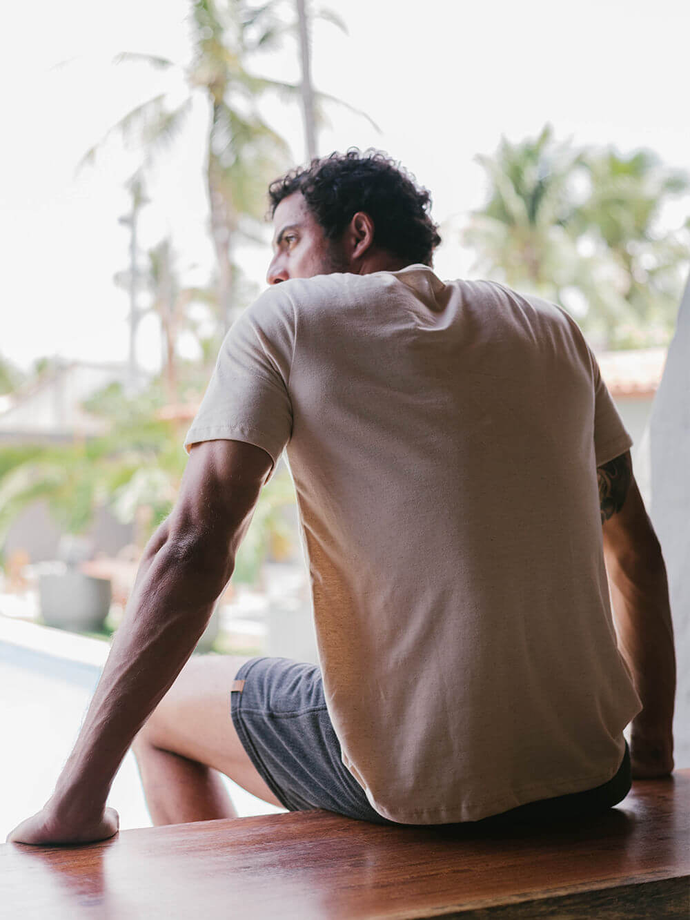 Camiseta Sunset bege da Greenish, vista traseira em ambiente tropical, estilo casual e confortável.