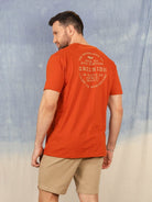 Camiseta Greenish The Waveriders Co. - Telha vista de costas em fundo azul e nuvens.