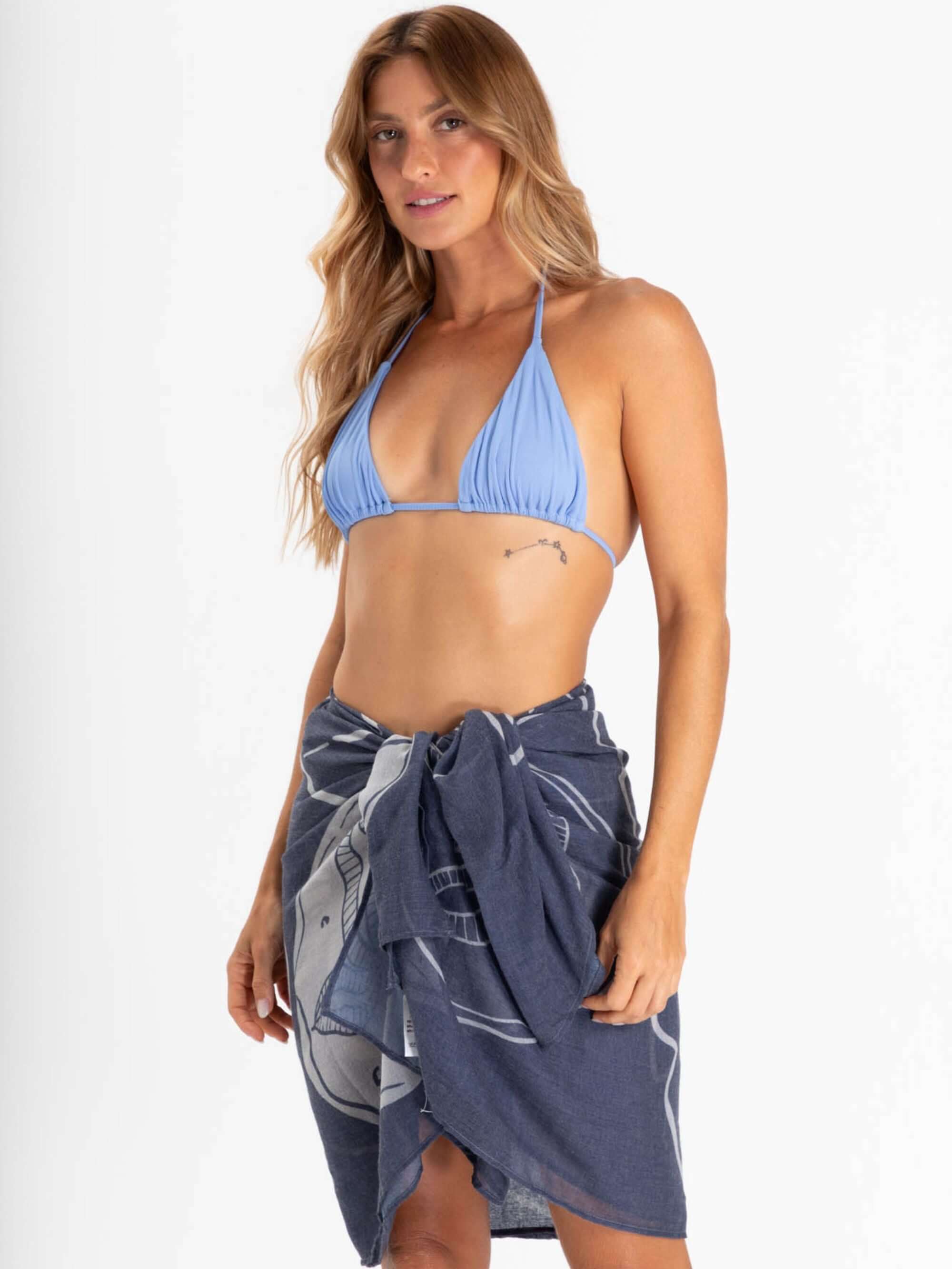 Canga handmade Sand Dollar azul marinho da marca Greenish, usada como saia por modelo em praia.