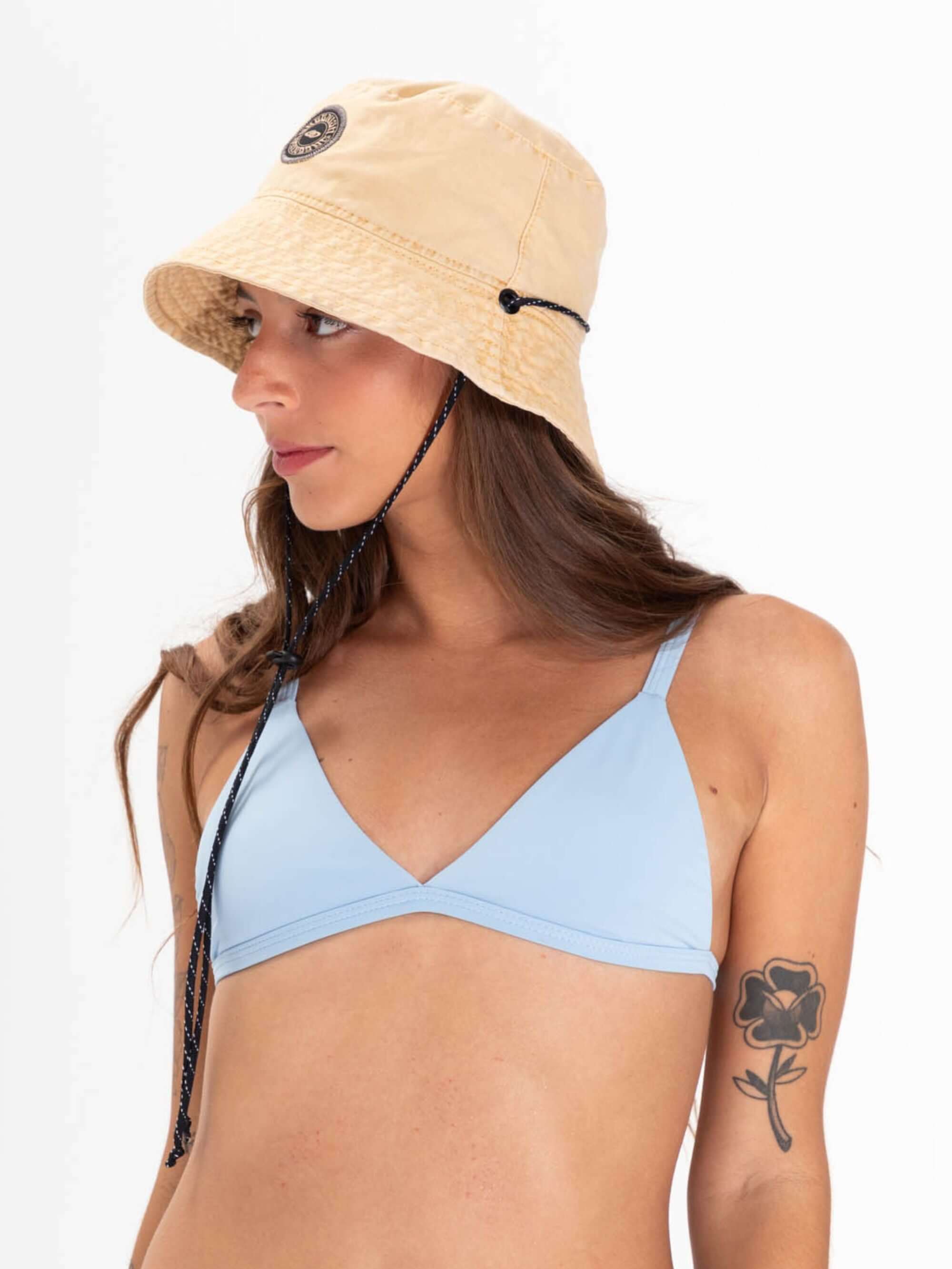 Modelo usando chapéu bucket tingido bege da marca Greenish, combinando estilo e proteção solar.