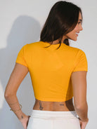 Cropped Zoey Laranja da Greenish, vista traseira, modelo usando top laranja, estilo casual.