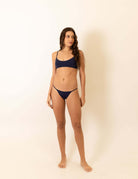 Mulher usando o Biquini Fixo Essential - Azul Marinho da marca Greenish, destacando conforto e estilo.