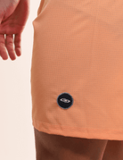 Boardshort Sunset Laranja da Greenish em detalhe, mostrando tecido leve e bolso lateral. Ideal para conforto e performance na água.