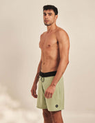 Man wearing Greenish Boardwalk Sunny Vibes Collor - Verde shorts, classic 44cm shape, perfect for beach and street wear.