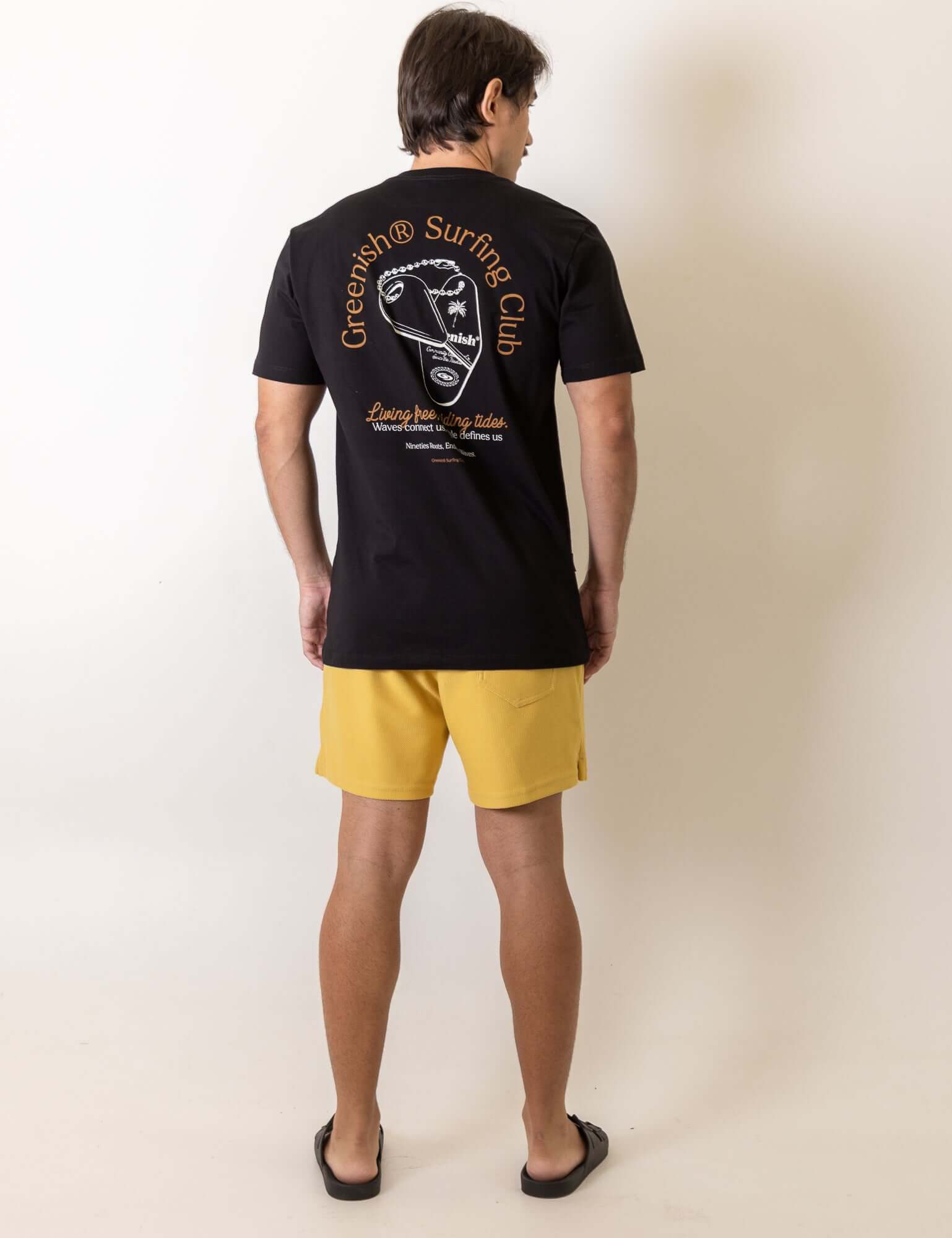 Homem vestindo Camiseta Fin Key - Preto da Greenish com design vintage e espírito surfista, destacando bordado retrô nas costas.