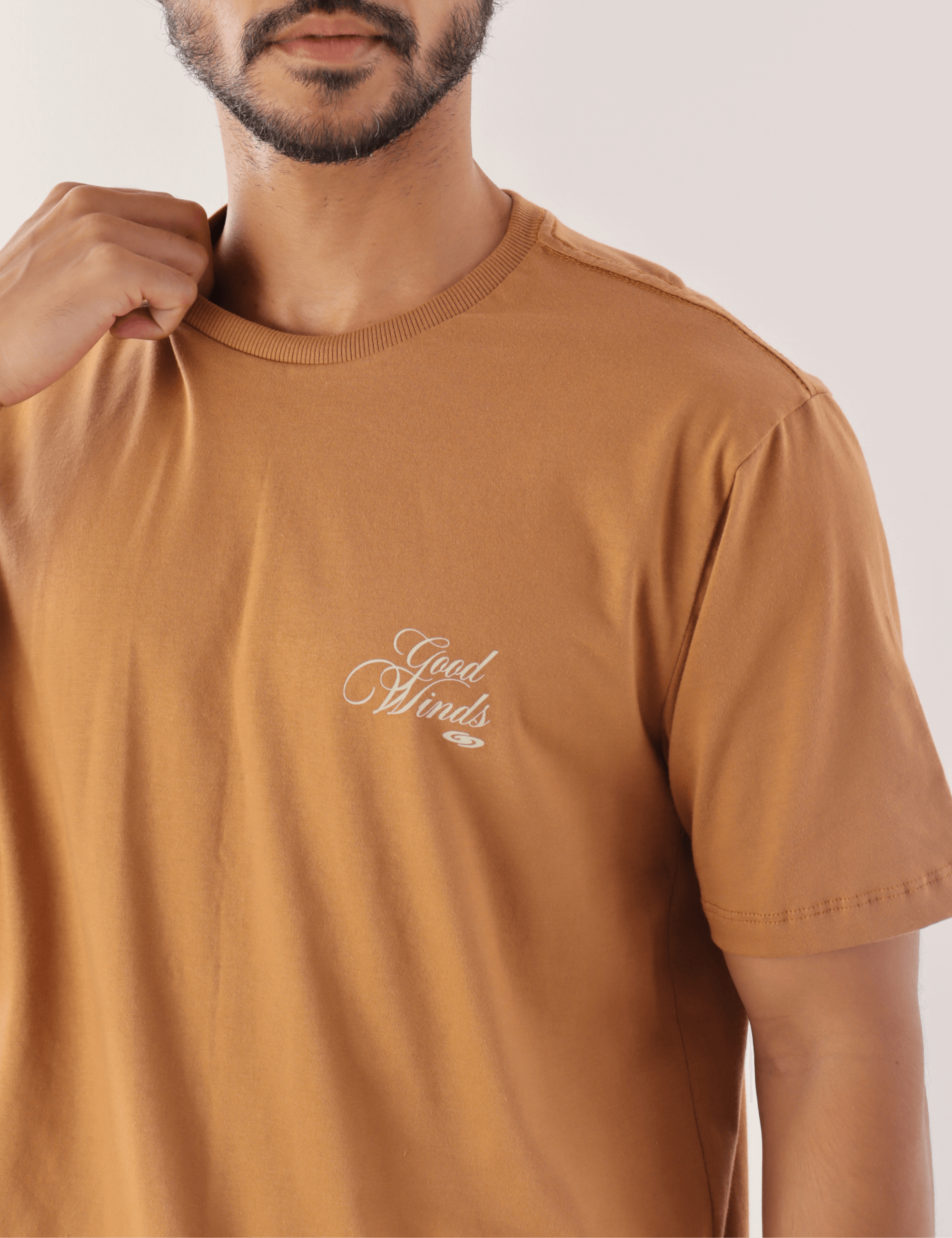 Homem vestindo camiseta marron 'Kites & Good Winds' da Greenish, destacando o design elegante e confortável para amantes de esportes ao ar livre.