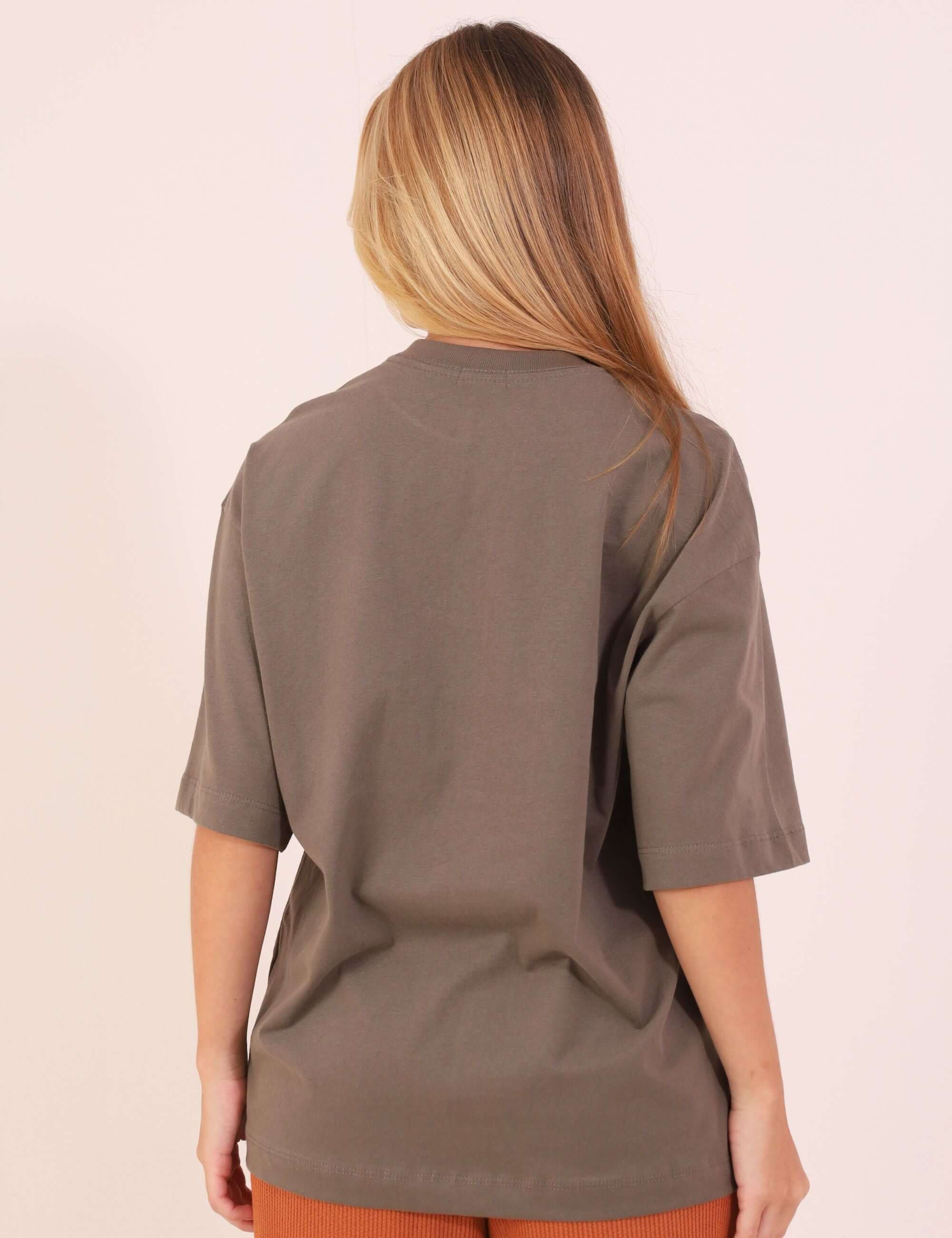 Modelo usando CAMISETA OVERSIZED GREENISH BORDADA - VERDE ESCURO, vista das costas, destacando tecido suave e caimento confortável.