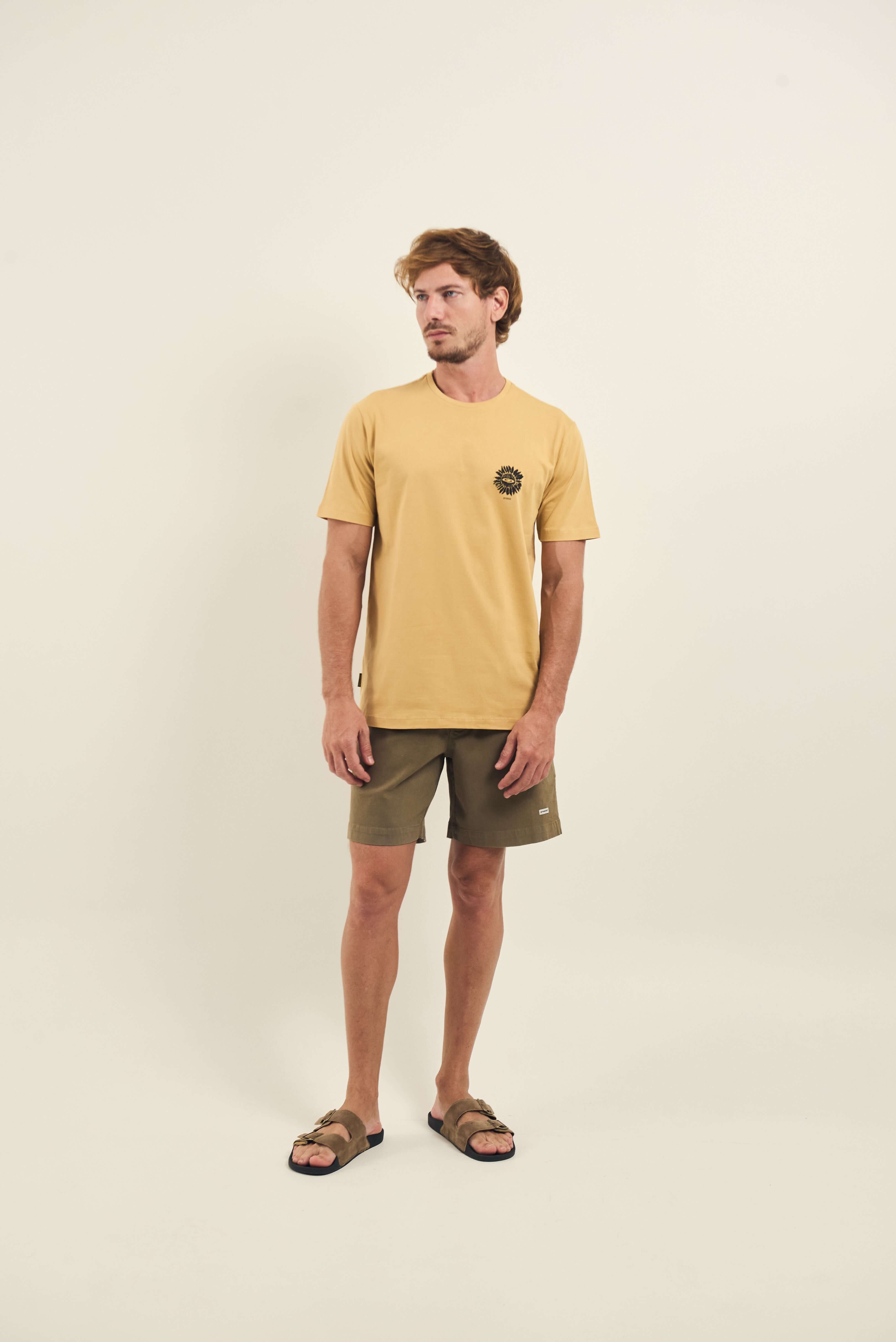 Modelo vestindo Camiseta Sunflowers Poster - Caqui da marca Greenish com design casual e moderno, shorts verdes e sandálias marrons.