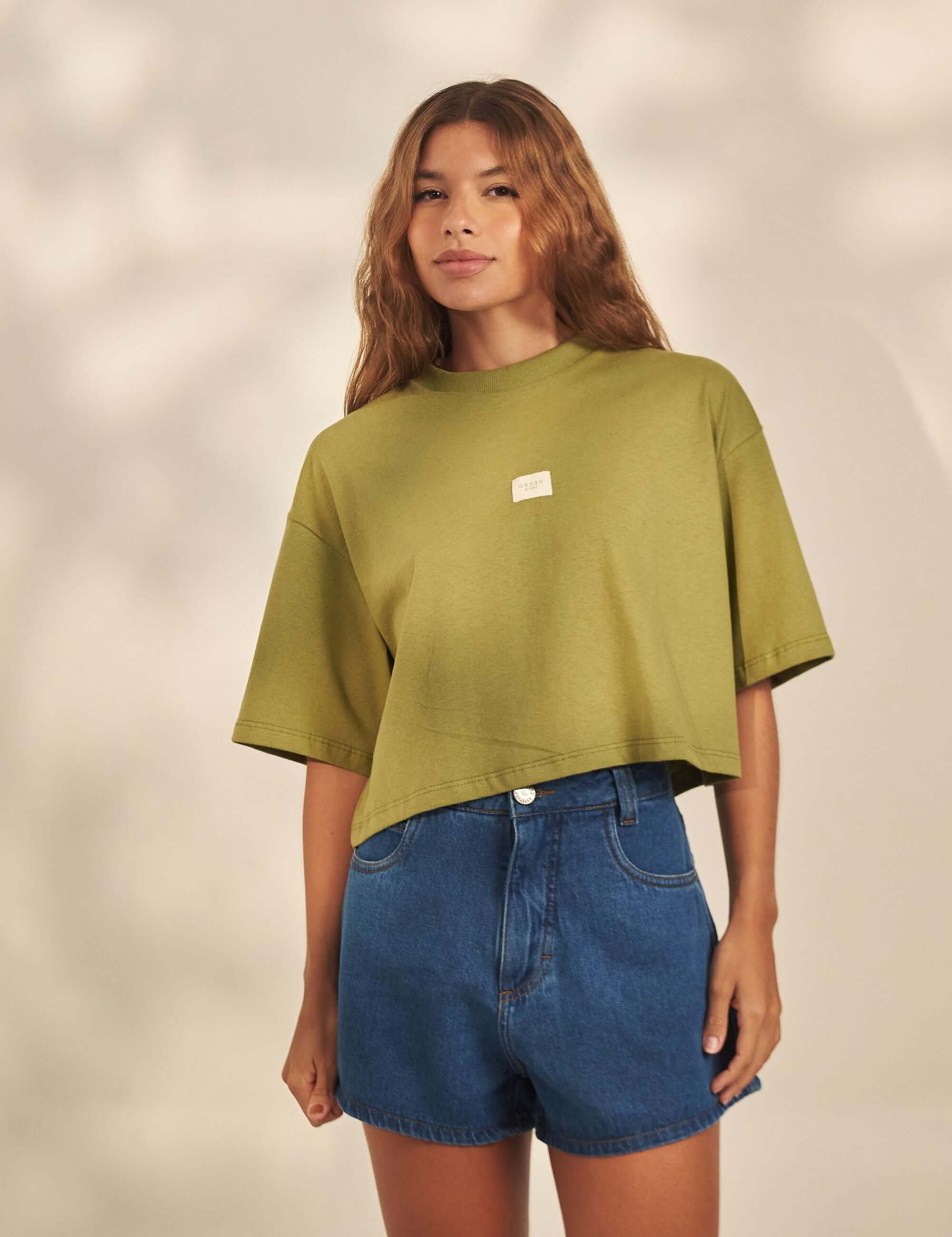 Cropped Oversized Grnsh - Verde Greenish: modelo usando camiseta cropped oversized em malha 100% algodão com etiqueta frontal e gola larga