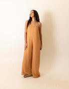 Mulher vestindo Macacão Leslie - Caqui da marca Greenish, destacando elegância e conforto. Peça chave para seu guarda-roupa.