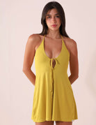 Woman wearing Macaquinho Curto Flora - Amarelo with adjustable tie-straps and a lightweight, soft fabric for sunny days.