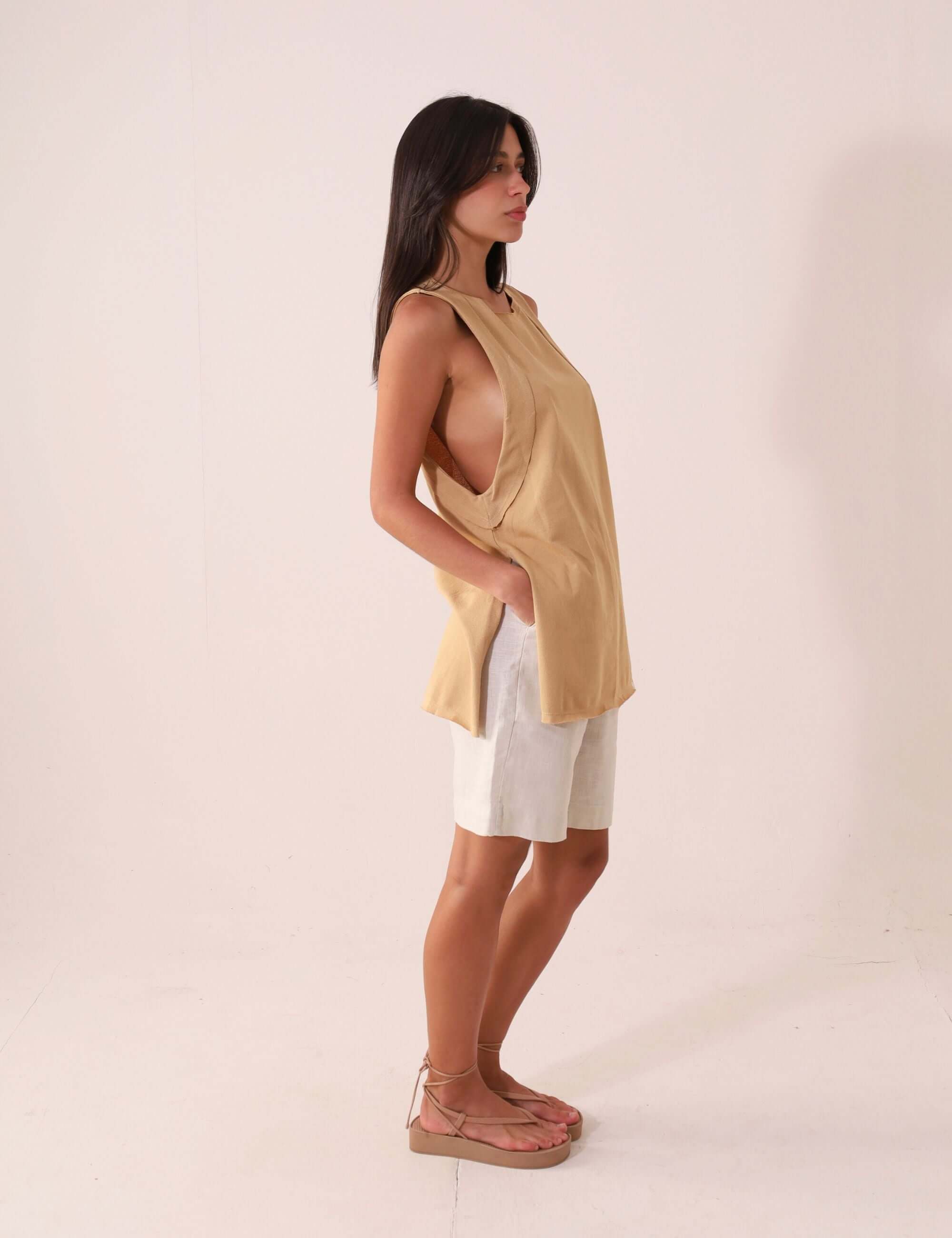 Mulher vestindo a Regata Déa - Caqui da Greenish, exibindo design cavado e fendas laterais para looks casuais e confortáveis.