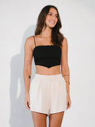 Modelo usando o cropped Triângulo Dina preto da Greenish, estilo lenço, com shorts claros.