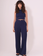 Mulher vestindo Calça Lina azul marinho da Greenish, feita em Tricot Bloom 100% algodão, com caimento reto e cintura média.