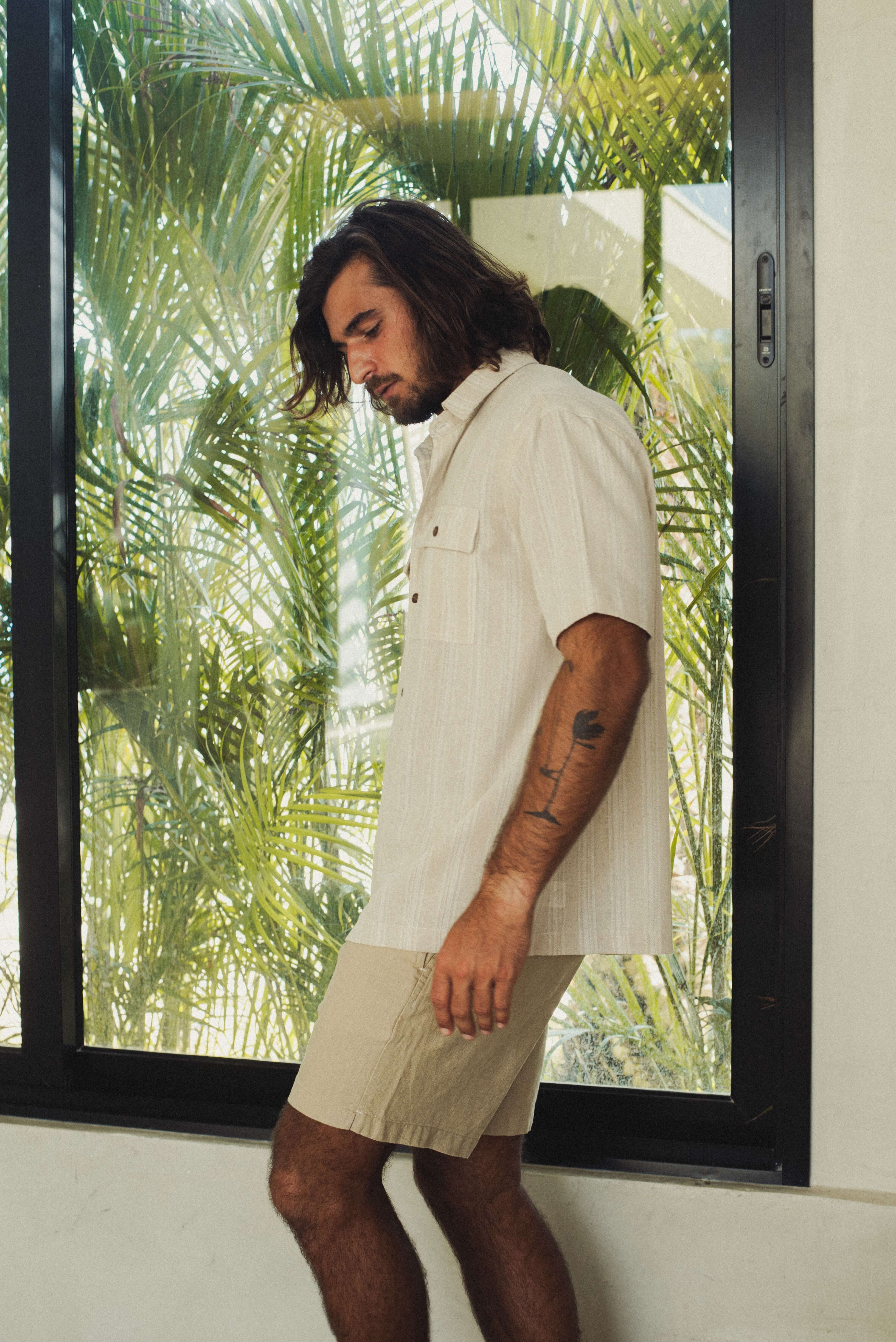 Modelo usando Camisa Botão Linho Listrado Oversized - Natural da marca Greenish em ambiente tropical.