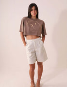 Modelo vestindo camiseta Greenish CROPPED STONE RELAXING VIEW - MARRON com estampa "Tropical Therapy", estilo casual e descontraído.