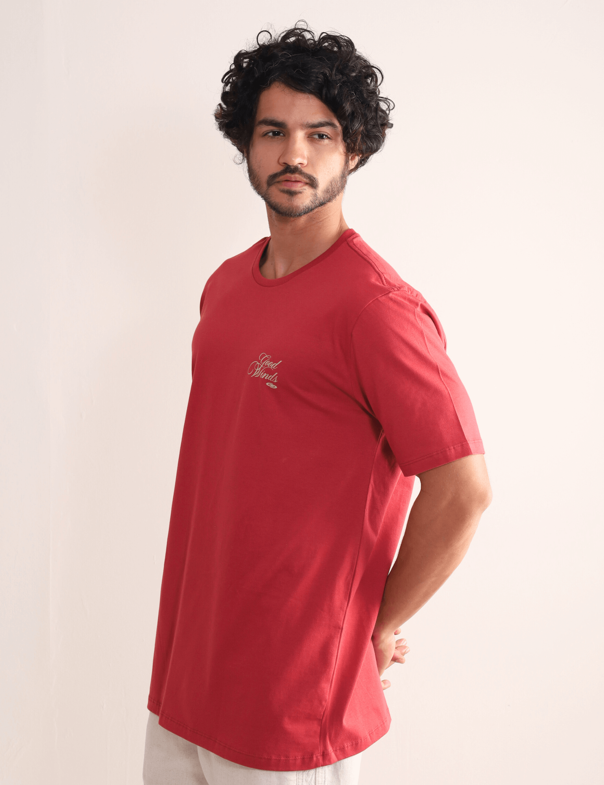 Homem usando Camiseta Vermelha Greenish "Kites & Good Winds", com bordado frontal. Conforto e estilo em algodão de qualidade.
