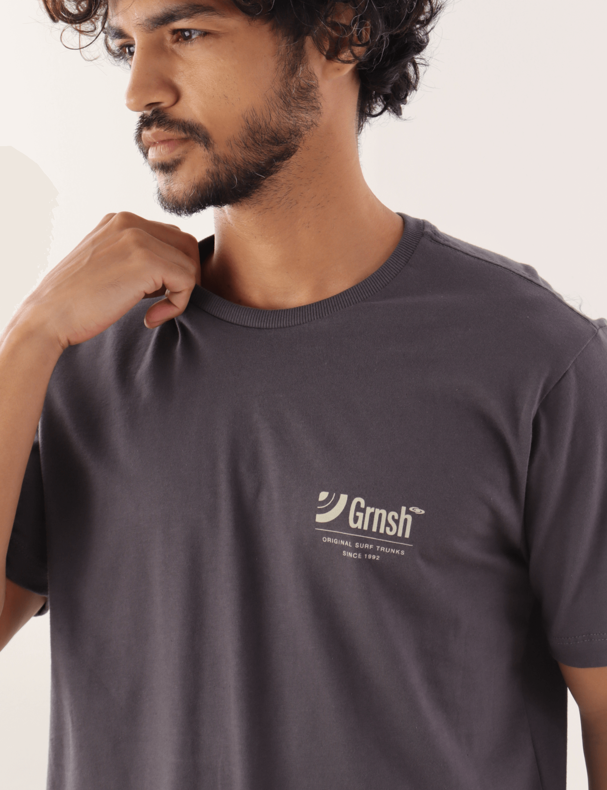 Homem usando Camiseta Originl Surf Trunks Série I Grafite da marca Greenish, destacando estilo casual e confortável.