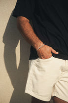 Homem vestindo Camiseta Oversized Strong - Preto da marca Greenish, destacando estilo casual com shorts claros e design marcante.