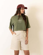 Modelo vestindo camiseta Greenish Cropped Oversized Stone Tropical Club - Verde, com estampa tropical, estilo vintage e toque macio.