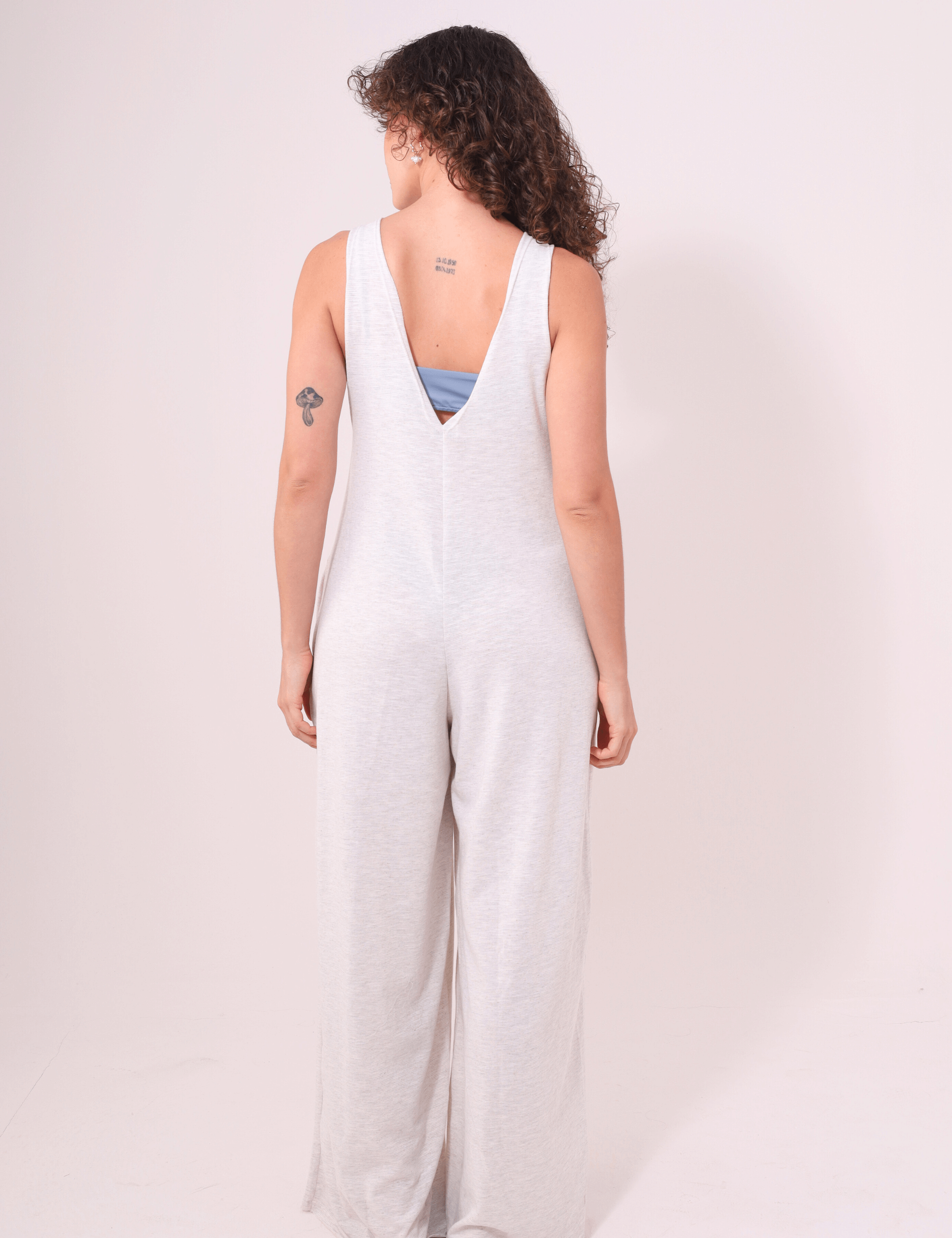 Alt Tag: Mulher vestindo Macacão Lais Natural marca Greenish, com decote V nas costas e pernas amplas, estilo confortável e casual.