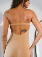Macacão Larissa bege da Greenish, com costas nuas e tatuagens visíveis, mostrando estilo e conforto.